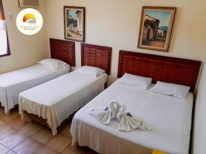a room with two beds with white sheets at Pousada Por do Sol in Paraty