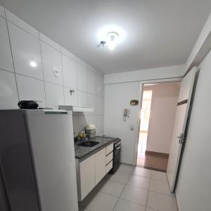 uma cozinha com armários brancos, um lavatório e um frigorífico em Flat 308 em Teresina