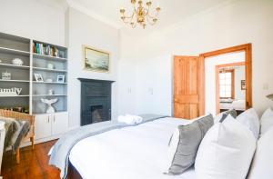 a white bedroom with a bed and a fireplace at Oceanfront Penthouse in Muizenberg