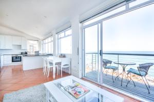 a kitchen and dining room with a large window at Oceanfront Penthouse in Muizenberg