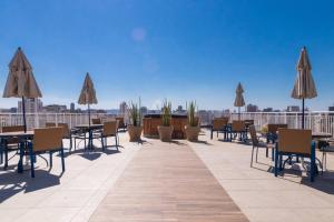 un patio con tavoli, sedie e ombrelloni di BHomy You a San Paolo