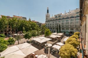 マドリードにあるApartments Madrid Principeの建物前のテーブルと白傘の通り