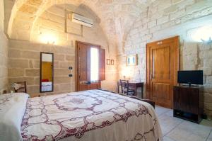 a bedroom with a bed and a tv in a room at Antica Corte B&B in Acquarica