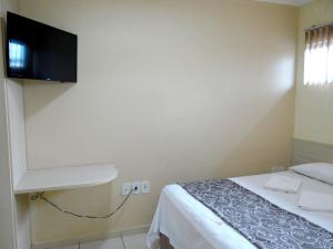 a bedroom with a bed and a flat screen tv at Hotel Via Oeste in Salgueiro