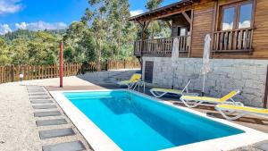 ヴィエイラ・ド・ミーニョにあるQuinta da Resteva-Chalé do RIOの建物の隣にプールがある家