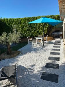 a patio with a table and an umbrella and chairs at Petit nid douillet en Luberon avec spa in Ansouis