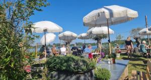 a group of people sitting at tables under white umbrellas at Casa The Wave with infrared sauna in Noordwijkerhout
