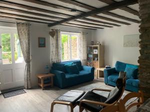 a living room with a blue couch and chairs at Hope Cottage in Modbury