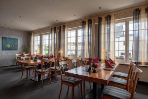 un restaurante con mesas y sillas de madera y ventanas en Hotel Schatulle en Laufersweiler