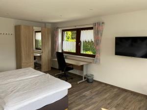 a bedroom with a bed and a desk and a television at Am Irrenbächle in Albstadt