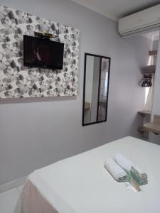 a room with a tv on a wall with a bed at Hotel Mandino in Alta Floresta