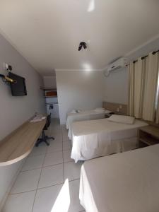 a hotel room with two beds and a tv at Hotel Mandino in Alta Floresta
