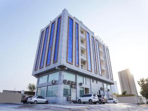 een hoog gebouw met auto's geparkeerd op een parkeerplaats bij SH Hotel - Free Parking in Ras al Khaimah