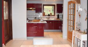 uma cozinha com armários vermelhos e um balcão branco em Les Cinq Francais em Nismes