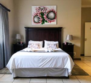1 dormitorio con 1 cama grande con sábanas blancas y flores en Waterval Self-Catering Holiday Home en Sabie