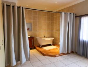 a bathroom with a tub and a shower curtain at Waterval Self-Catering Holiday Home in Sabie +21 photos