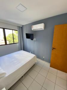 1 dormitorio con cama blanca y ventana en Flat Parque Jaqueira Home Service, en Recife