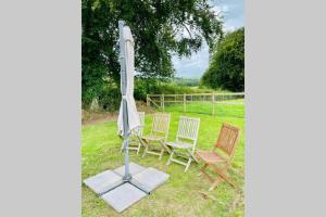 un groupe de chaises et un parasol dans l'herbe dans l'établissement Retro Mobile glamping - Near Dartmoor walks, à Exeter