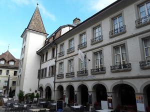 un grande edificio bianco con torre dell'orologio di Hostellerie du XVI Siècle a Nyon