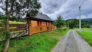 a wooden cabin in a field next to a dirt road at Dom Kormaniak in Korbielów