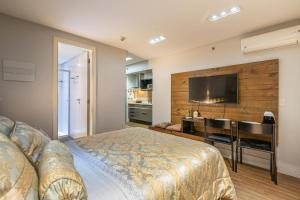 a bedroom with a bed and a desk and a television at Flat no Life com espetacular vista do lago in Brasilia