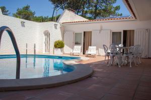 a pool with a table and chairs next to a house at Ofir Beach House Bonança in Esposende