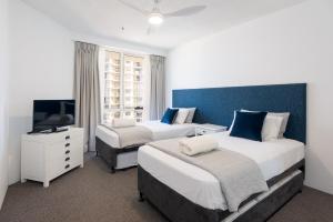 a hotel room with two beds and a television at Allunga Stunning Beach Side Apartment in Gold Coast