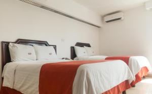two beds in a room with red and white sheets at Hotel Atenas in Xalapa