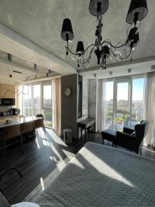 a bedroom with a bed and a dining room with windows at ACCOMMODO192 in Dnipro