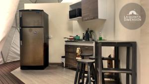 a kitchen with a refrigerator and a counter with stools at La Quinta Dimensión Glamping Resort in El Peñol