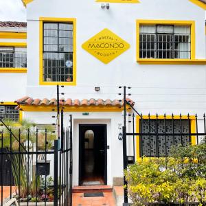 a white building with a blue door and a yellow sign at Hostal Macondo Bogotá in Bogotá