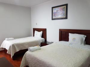 a bedroom with two beds with white sheets and a picture on the wall at Hotel Luz de Luna in Atico