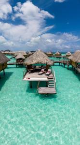 a resort in the water with chairs and umbrellas at Le Bora Bora by Pearl Resorts in Bora Bora