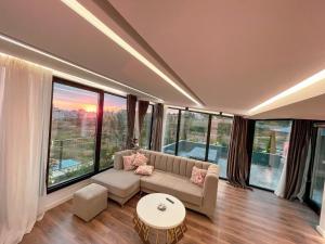 a living room with a couch and large windows at Perla Luxury Penthouse in Tirana