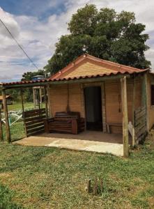 a small house with a porch in a field at Chalés e Camping Taquaral in São Thomé das Letras