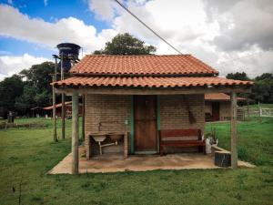 a small house with a bench in a field at Chalés e Camping Taquaral in São Thomé das Letras
