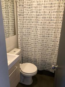 a bathroom with a toilet and a white shower curtain at Departamento Horizonte Playa la Herradura in Coquimbo