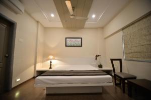 a bedroom with a bed and a table and a chair at Hotel Naman in Solapur