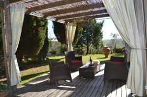 eine Holzterrasse mit Stühlen und einer Pergola in der Unterkunft Villa with swimming pool - air conditioning - Siena - 10 people - Tuscany crete in Asciano