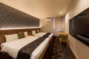 Habitación de hotel con 2 camas y TV de pantalla plana. en GRAND BASE -Nagoya Chiyokura- en Nagoya