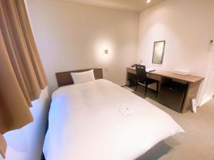 ein Hotelzimmer mit einem Bett und einem Schreibtisch mit einem Computer in der Unterkunft Hotel chez toi Kanonji in Kanonji