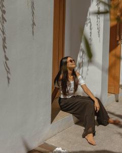 une femme assise sur les marches d'un bâtiment dans l'établissement Tiga Studios - Adults Only, à Kuta Lombok