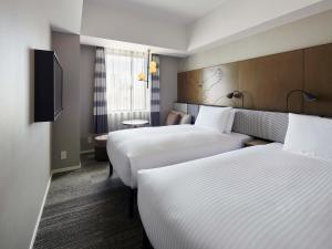 札幌市にある札幌グランベルホテルのベッド2台とテレビが備わるホテルルームです。