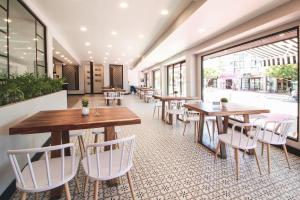 a restaurant with wooden tables and white chairs at Hotel Casa del Sol in Ensenada