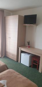 ein Schlafzimmer mit einem Schreibtisch und einem TV darüber in der Unterkunft Pensiunea Confort in Buşteni