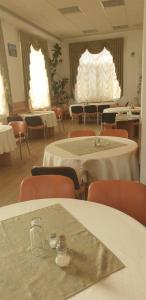 uma sala com mesas e cadeiras e mesas e cadeiras brancas em Pensiunea Confort em Buşteni