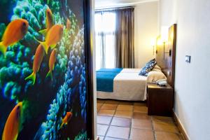 a hotel room with a bedroom with a bed and a mirror at Hotel Albaida Nature in Mazagón