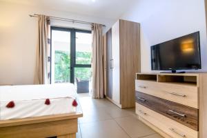 een slaapkamer met een tv en een groot raam bij Two Bedroom Apartment with Garden and Pool Access - Azuri Village, Roches Noires in Roches Noires