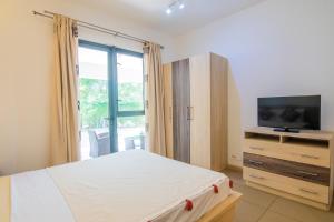 1 dormitorio con 1 cama, TV y ventana en Two Bedroom Apartment with Garden and Pool Access - Azuri Village, Roches Noires, en Roches Noires