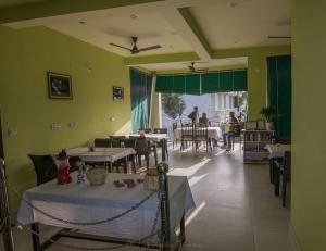 a restaurant with tables and people sitting at tables at Sanctuary Tourist Lodge in Bharatpur +4 photos